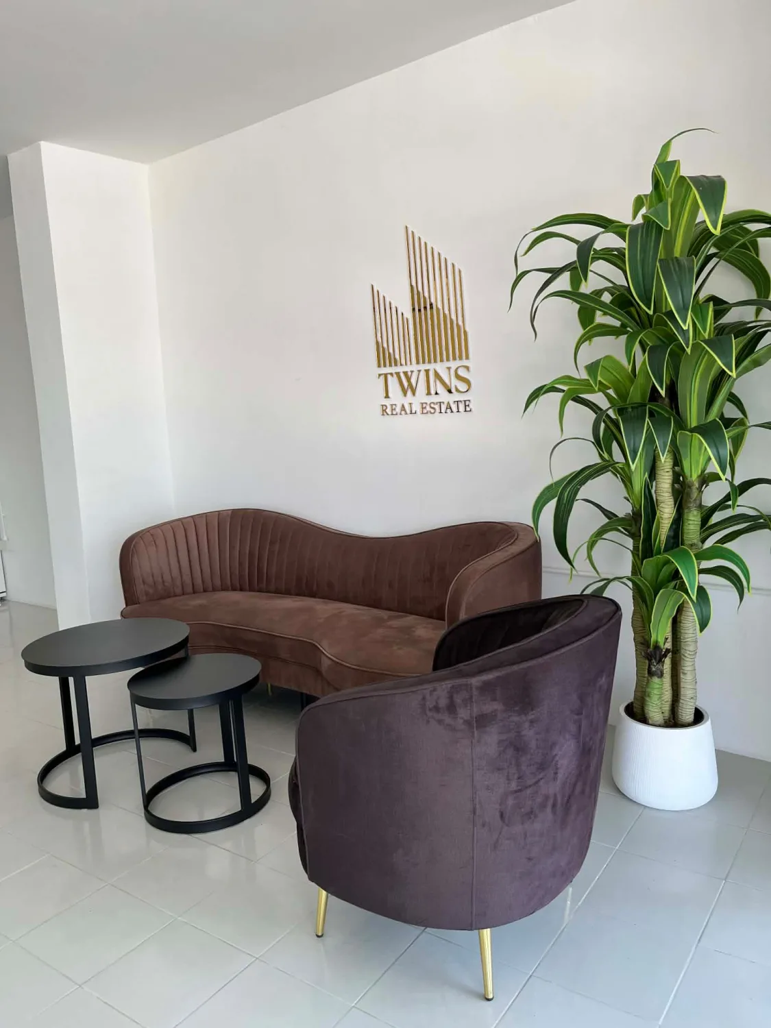 Strefa poczekalni w biurze Twins Real Estate ze złotym logo firmy